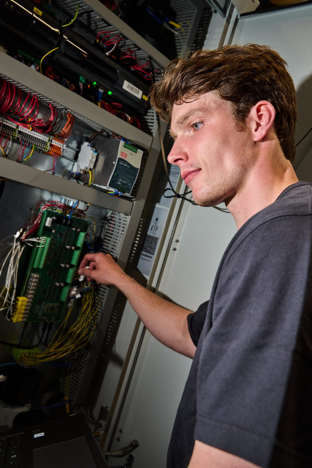 Martijn Oortwijn working at the open electrical cabinet of the test rig