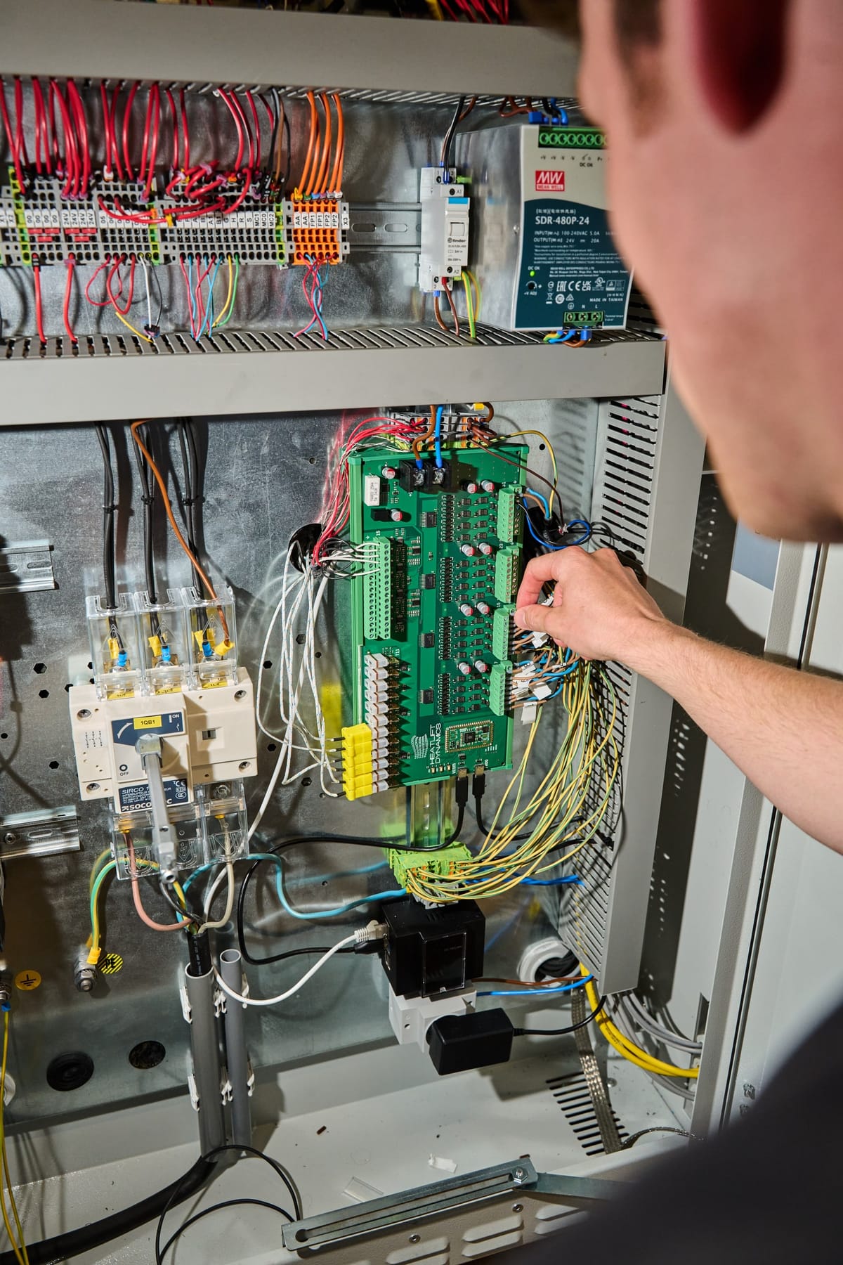 An engineer wiring the control board inside the test rig's electrical cabinet