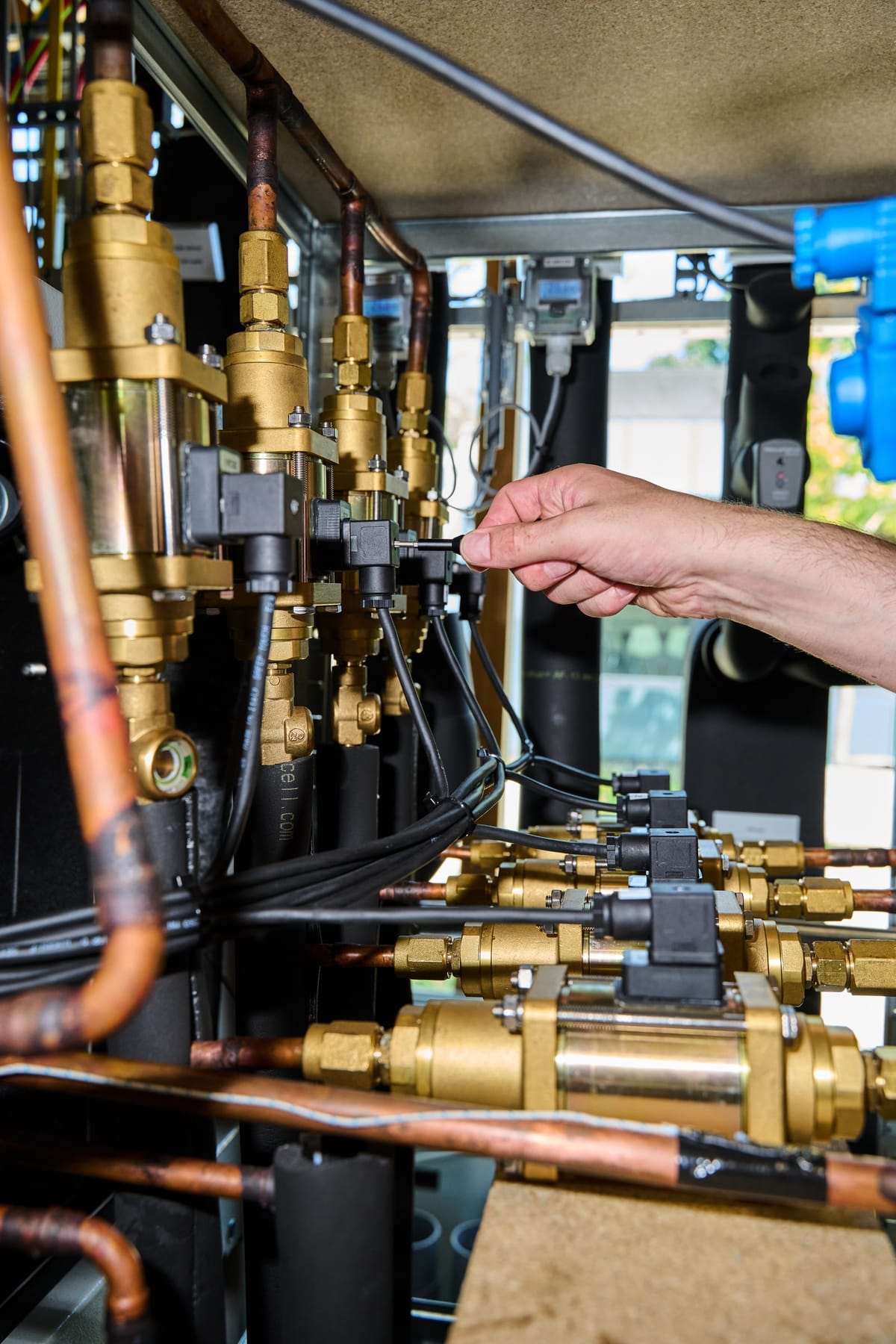 An engineer's hand adjusting a valve on the brass valve bank of the test rig