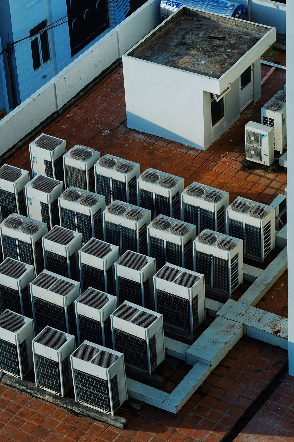 Rows of outdoor heat pump and air-conditioning units on a flat roof, seen from above
