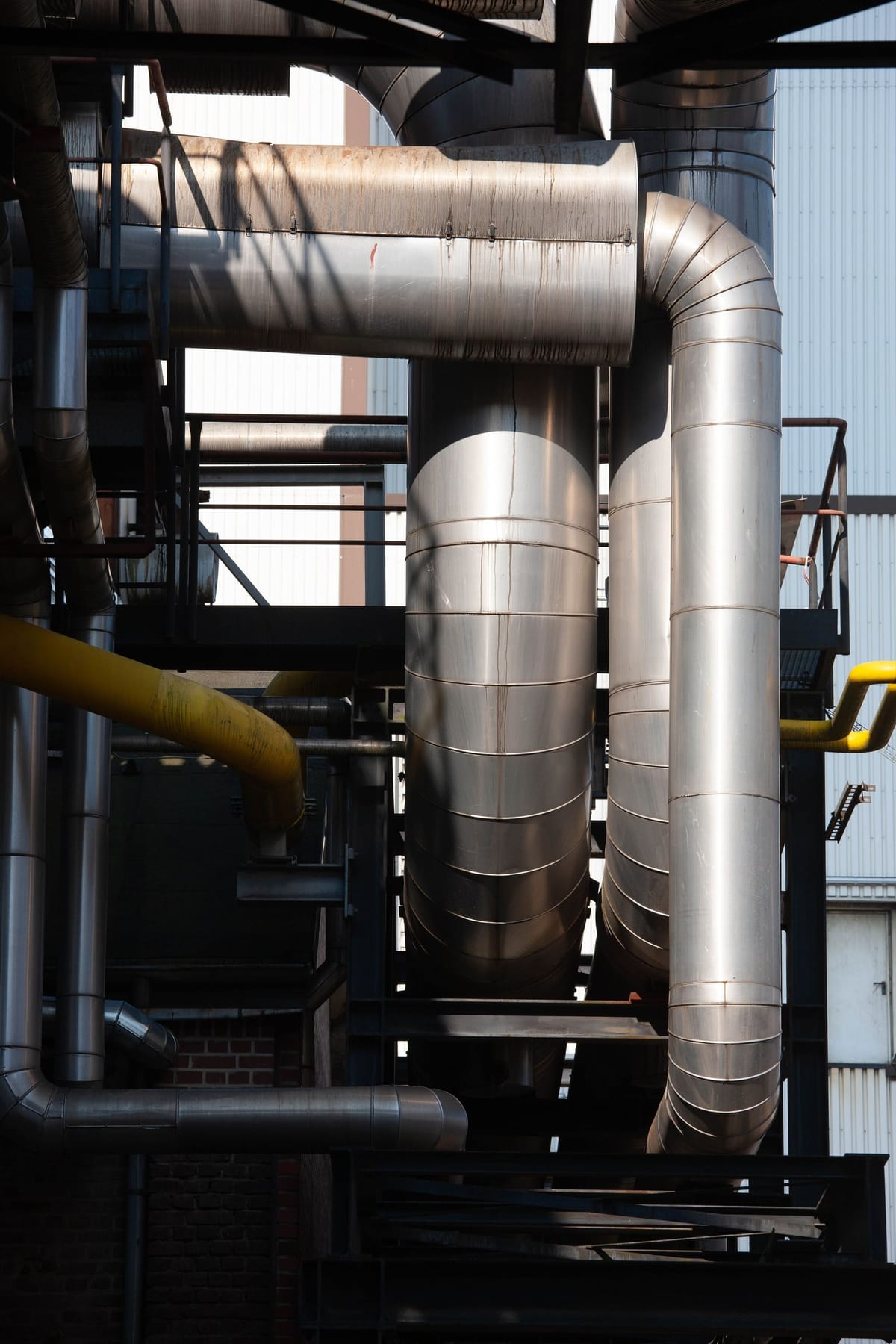 Insulated stainless steel process pipework and yellow gas lines on an industrial site