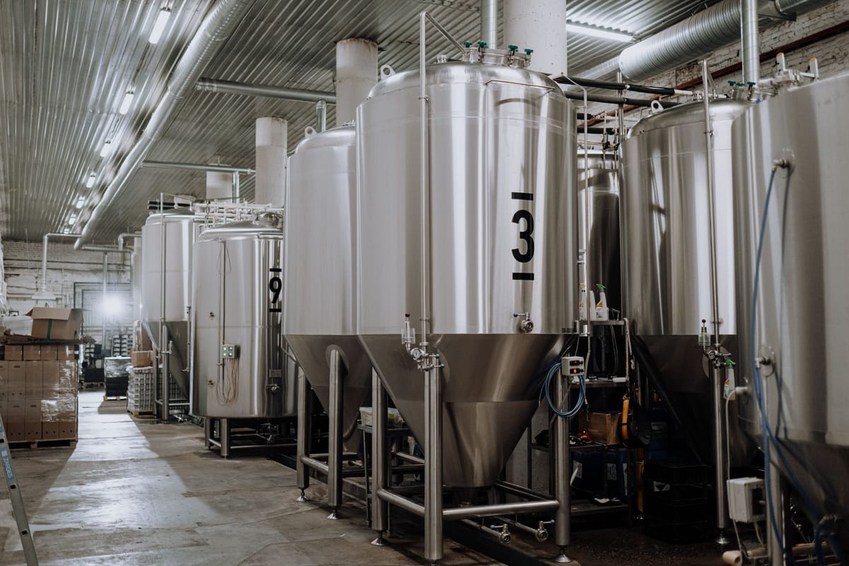 Row of stainless steel conical fermentation tanks in a brewery