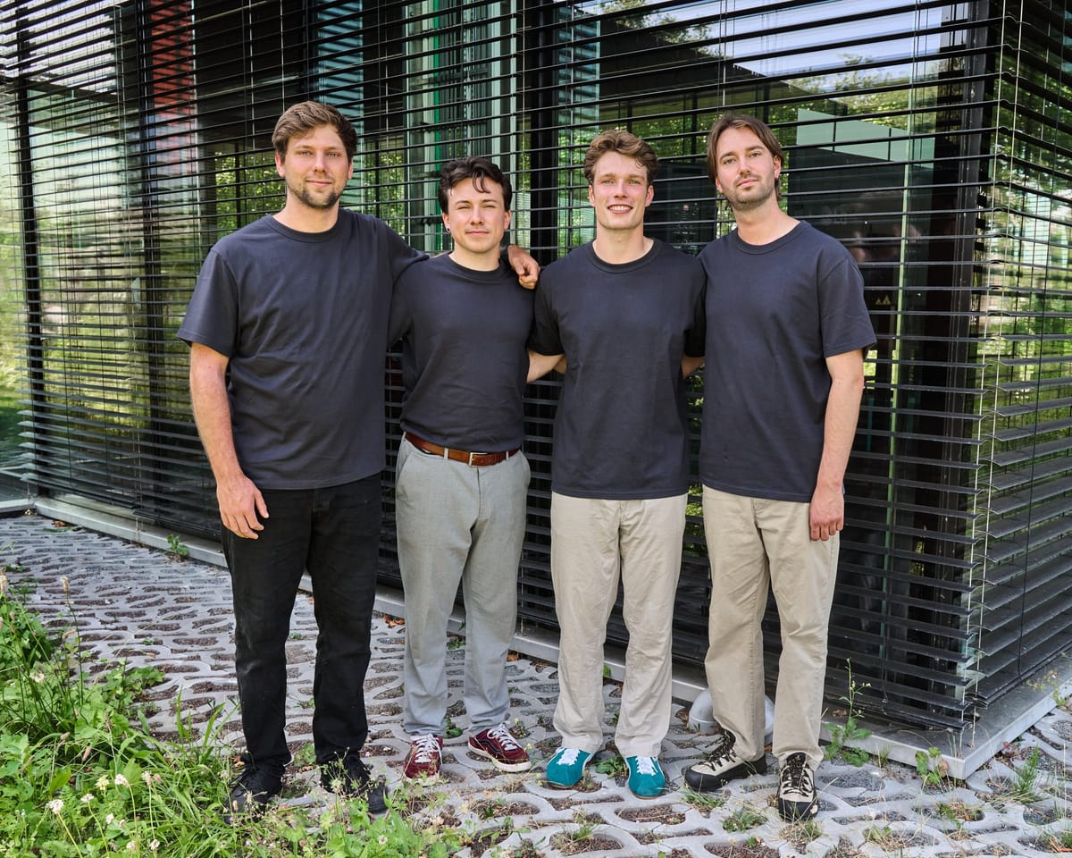 The four-person Expantec team standing together outside the louvred glass facade of the Yes!Delft building